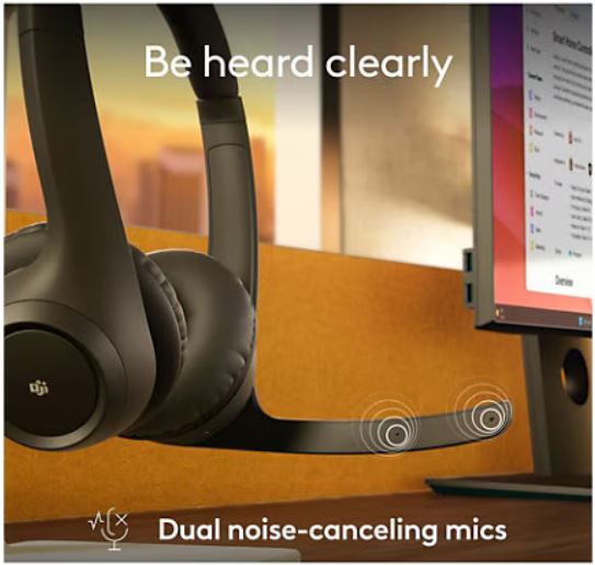 Headphones with dual noise-canceling mics in front of a computer setup
